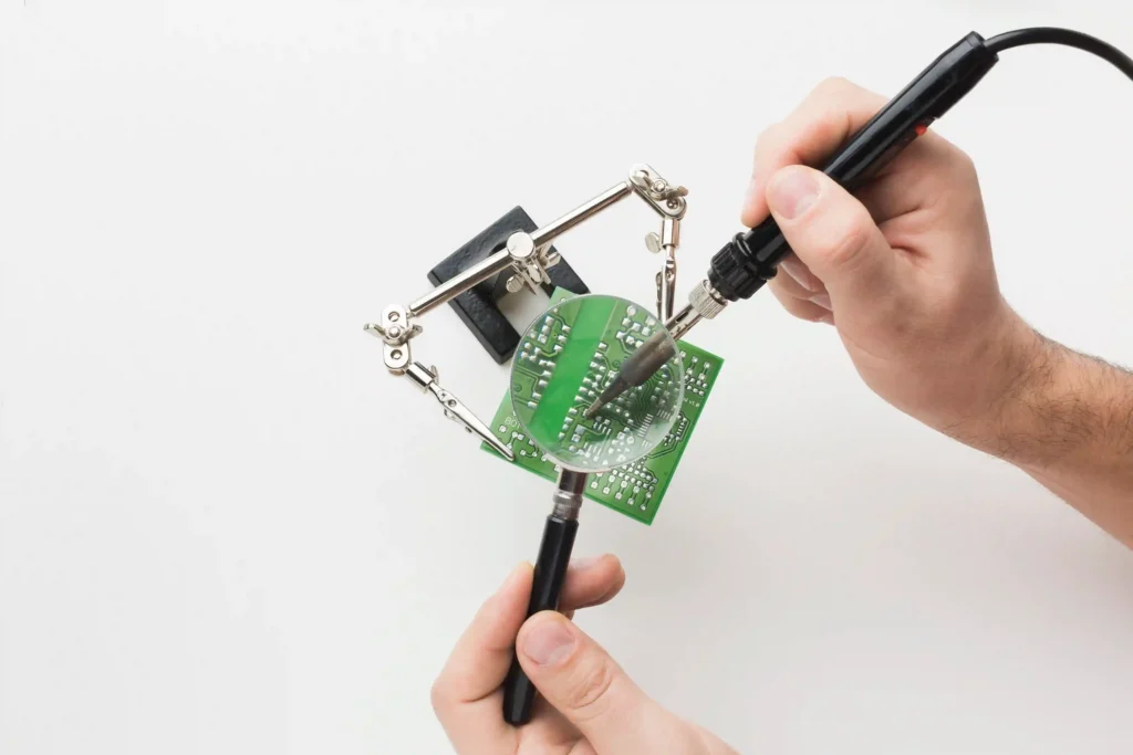 Hands soldering a mobile phone circuit board with a magnifying glass, highlighting the technical skills and detailed work involved in advanced device repairs